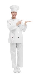 Happy woman chef in uniform pointing at something on white background