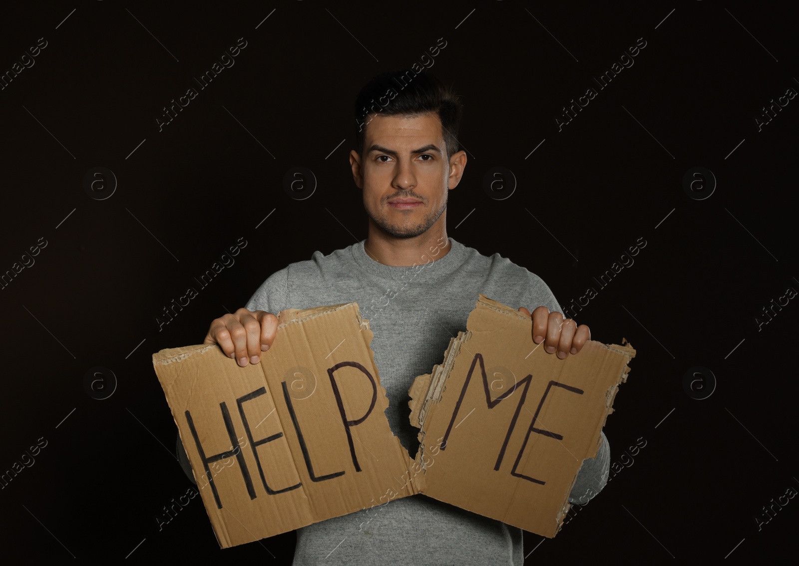 Photo of Unhappy man with HELP ME sign on dark background