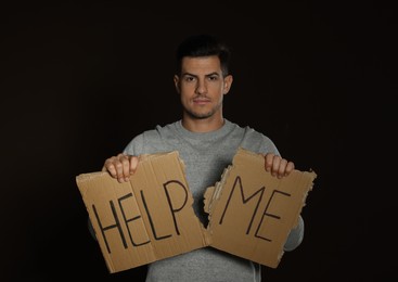 Unhappy man with HELP ME sign on dark background