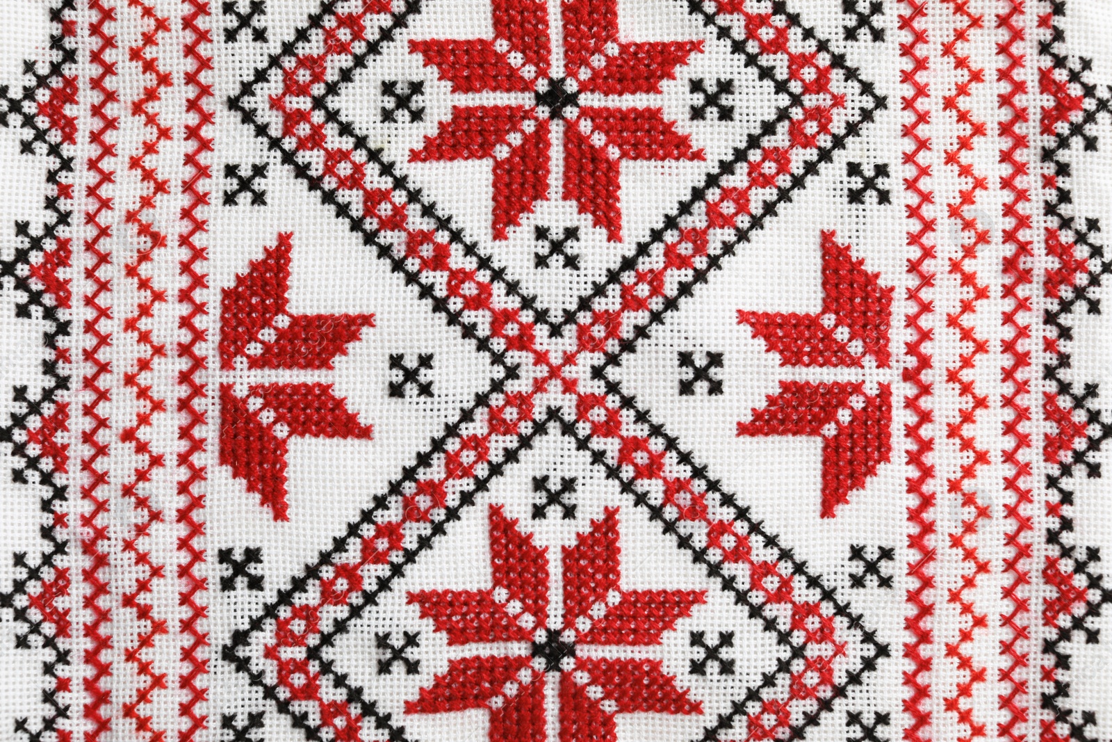 Photo of Traditional Ukrainian embroidery on white canvas as background, closeup. National handicraft