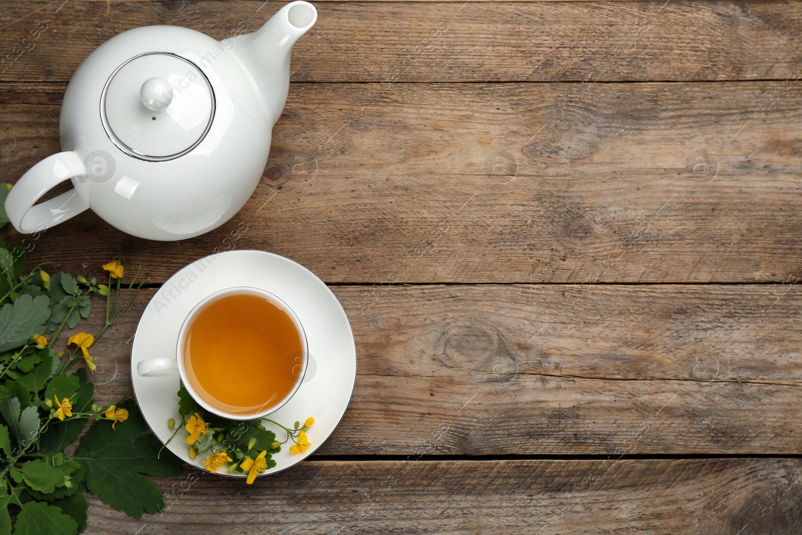 Photo of Aromatic celandine tea and flowers on wooden table, flat lay. Space for text