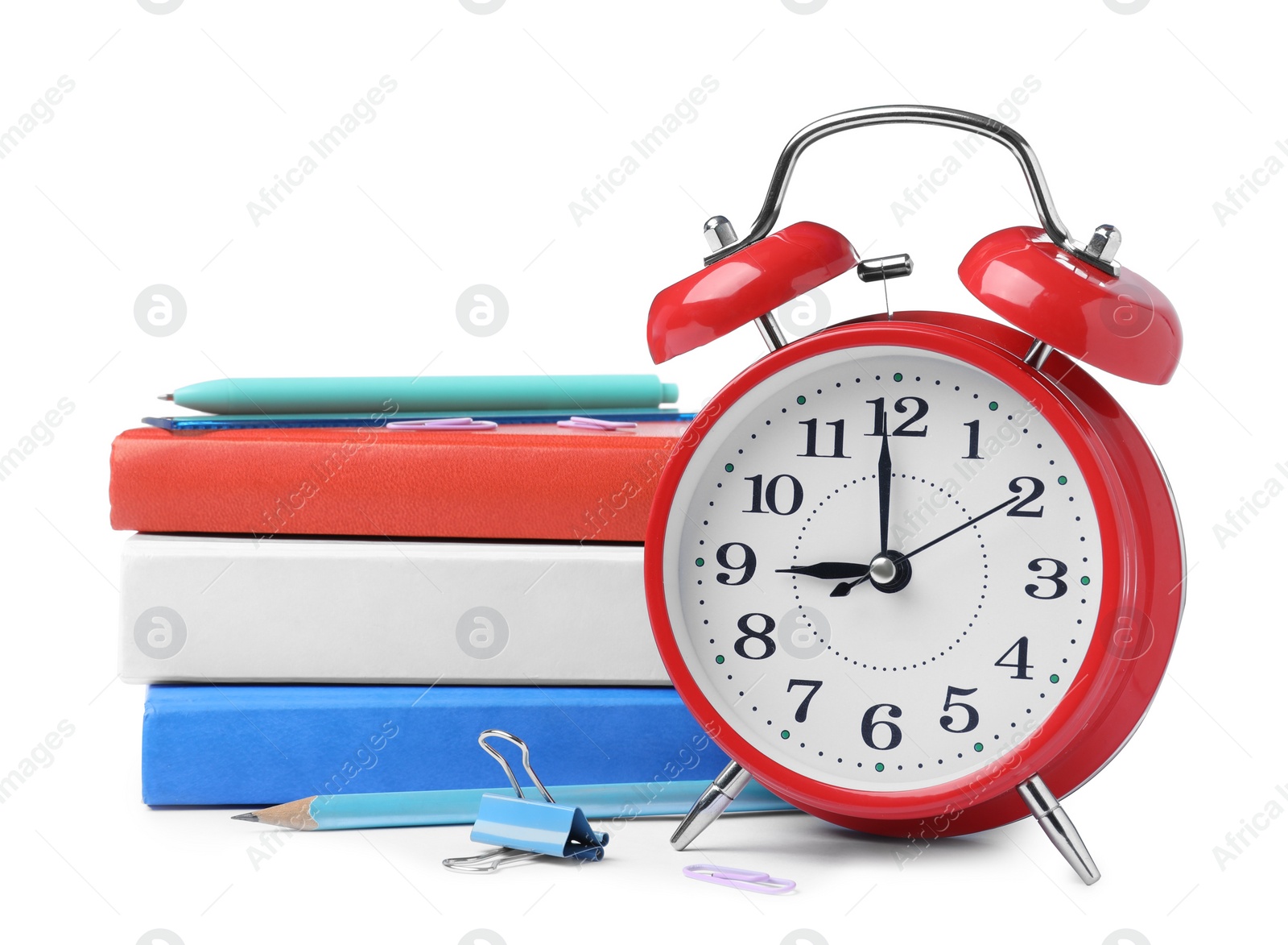 Photo of Red alarm clock and different stationery on white background. School time