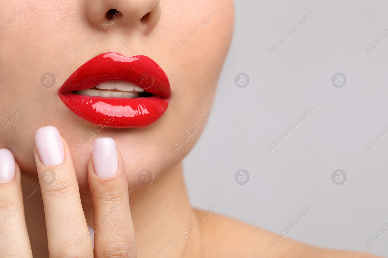 Photo of Young woman with perfect lips makeup on light background, closeup. Space for text