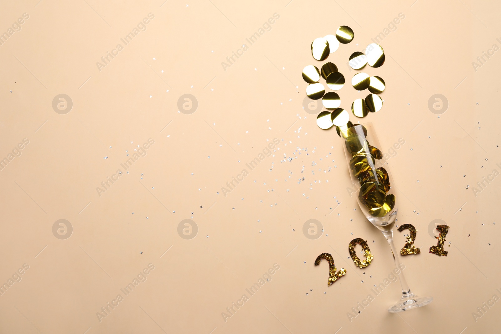 Photo of Year number 2021, glass and shiny confetti on beige background, flat lay. Space for text