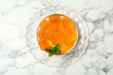 Orange jelly in bowl on marble table, top view