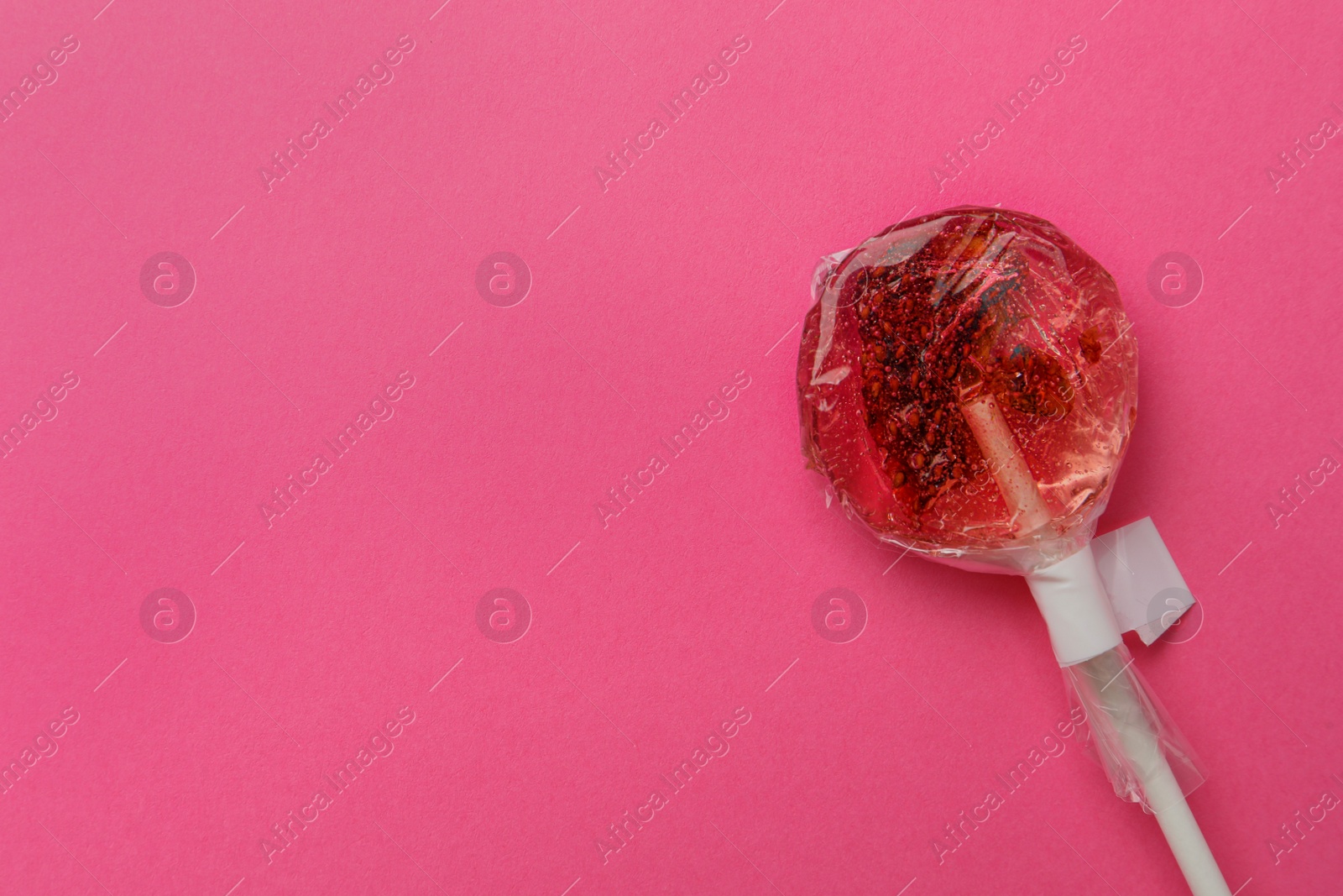 Photo of Sweet colorful lollipop with berries on pink background, top view. Space for text