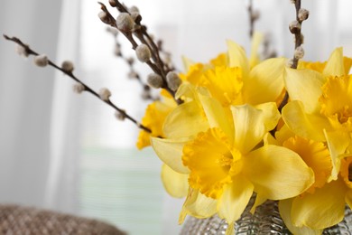 Photo of Bouquet of beautiful yellow daffodils and willow twigs on blurred background, closeup