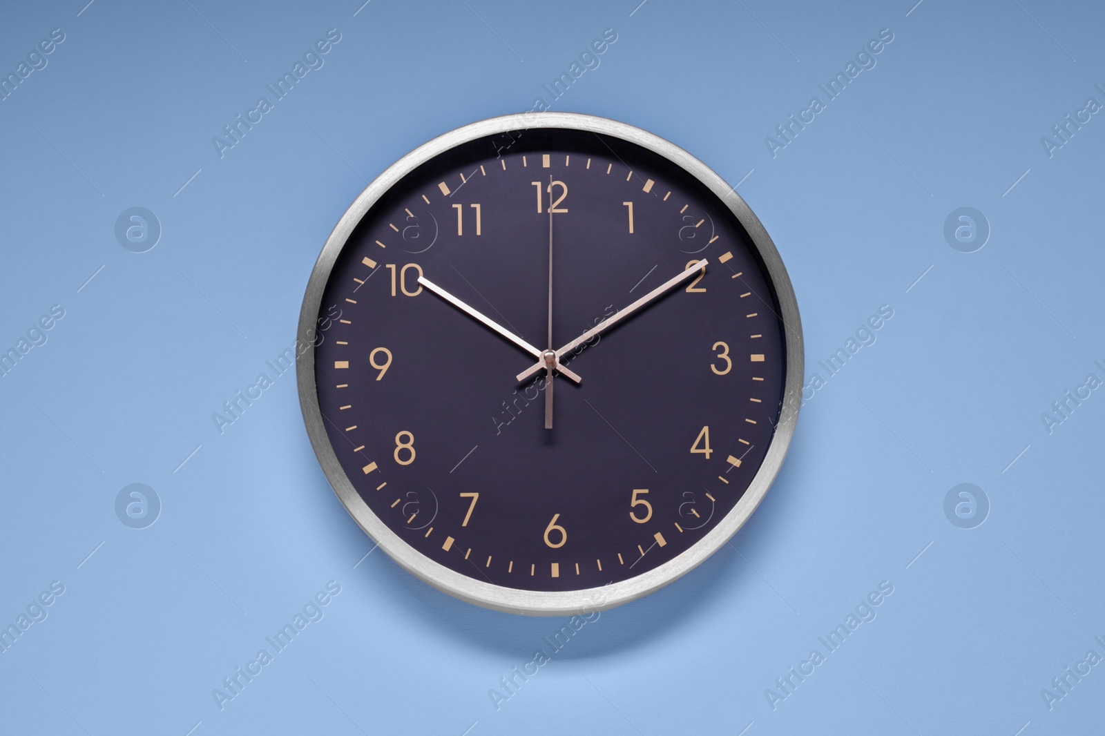 Photo of Stylish round clock on light blue background, top view. Interior element