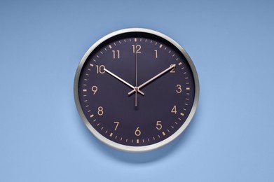 Photo of Stylish round clock on light blue background, top view. Interior element