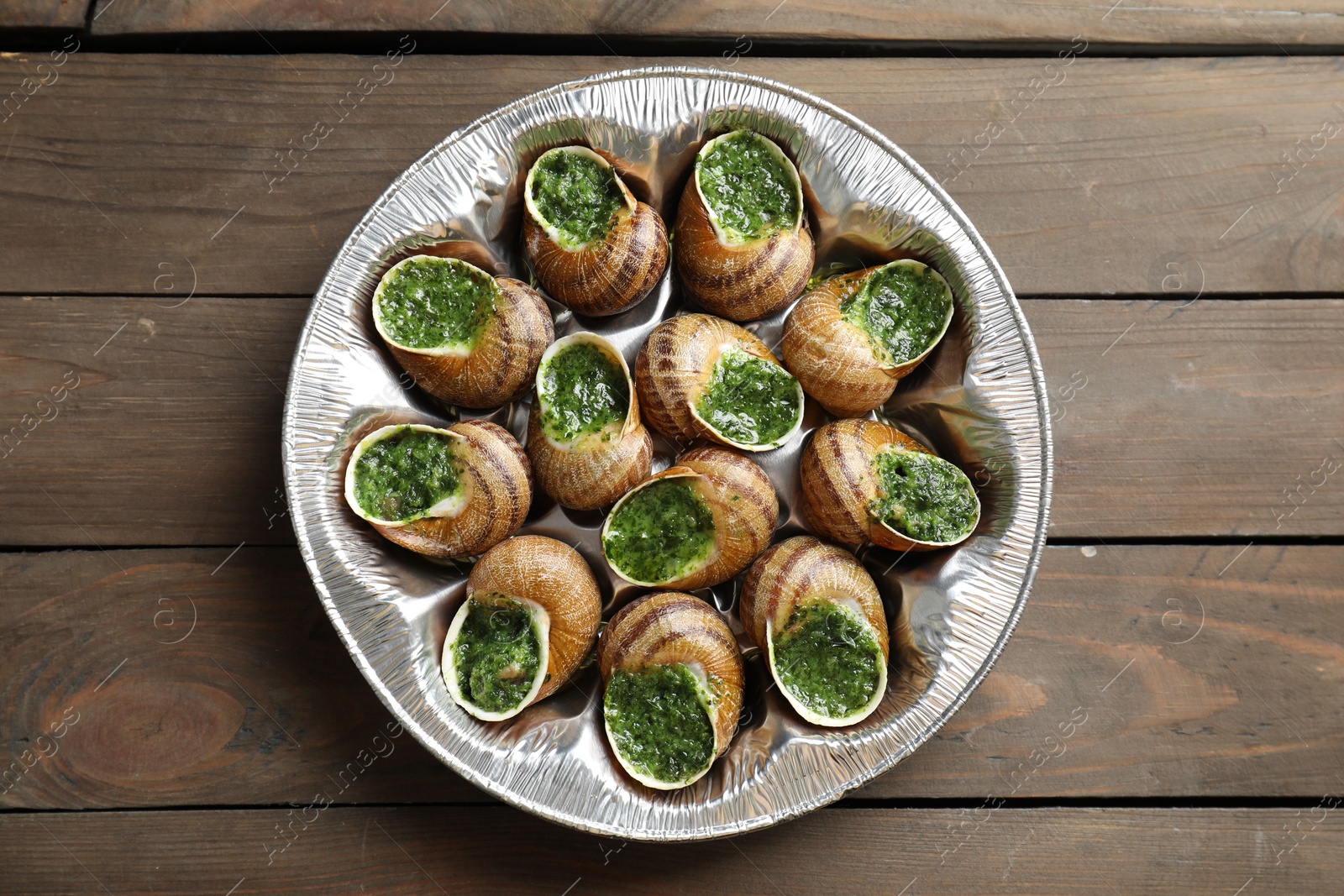 Photo of Delicious cooked snails on wooden table, top view