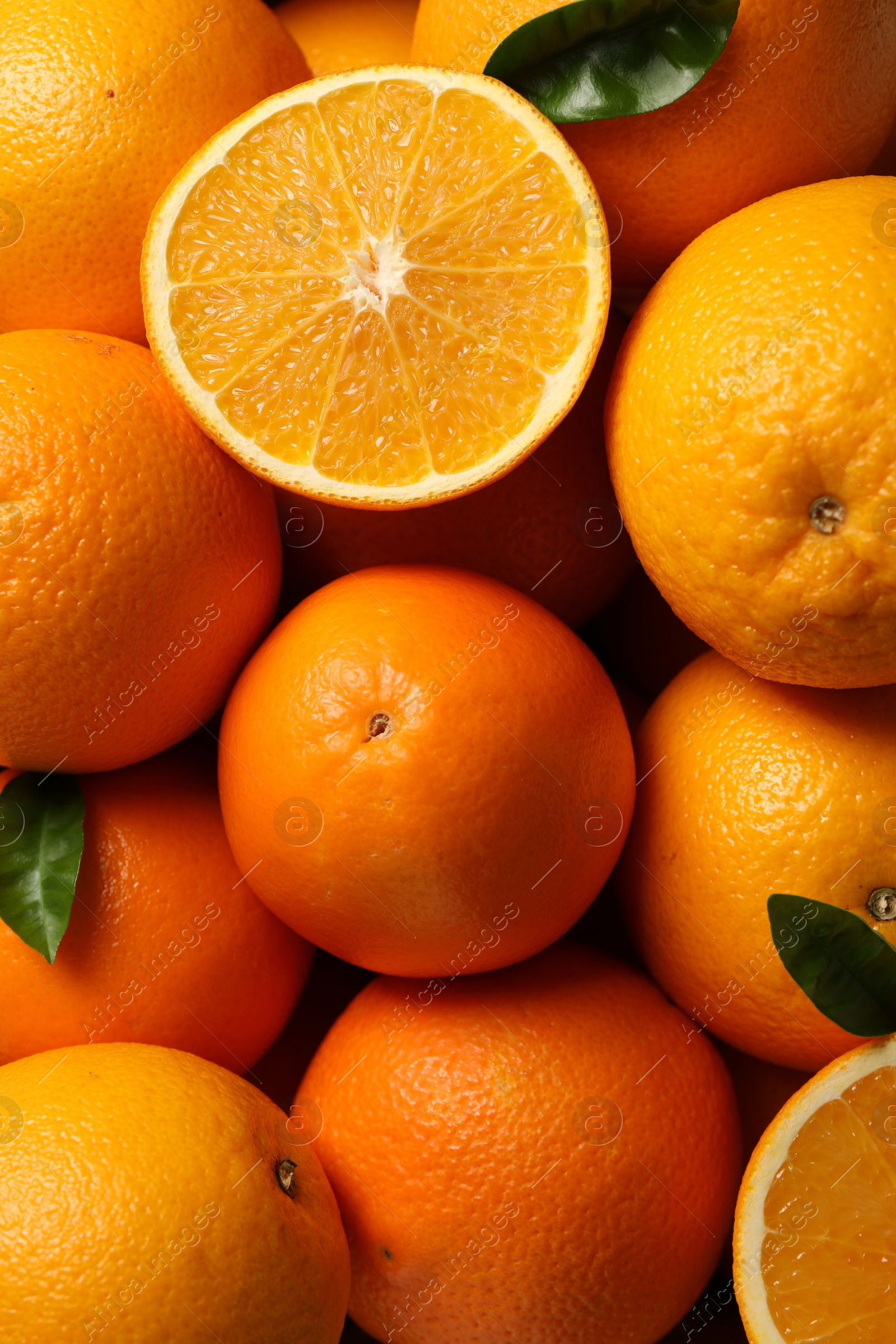 Photo of Many ripe oranges and green leaves as background, top view