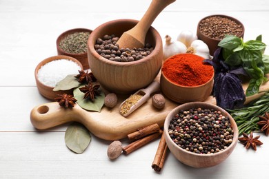 Mortar with pestle and different spices on white wooden table