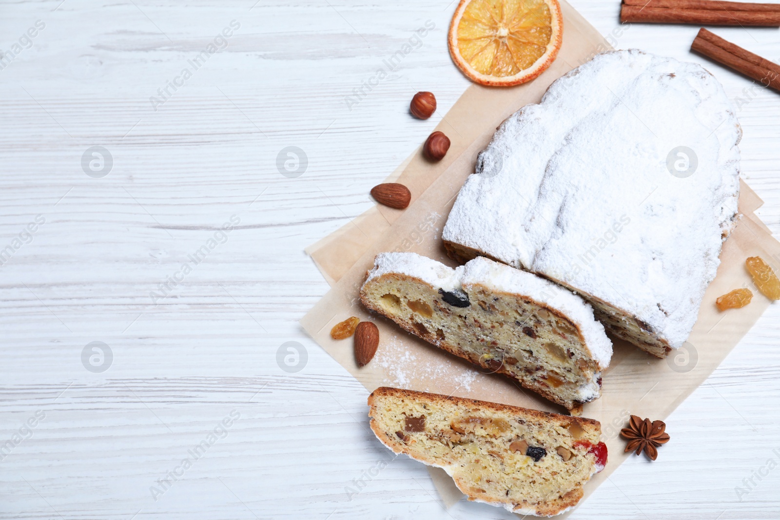 Photo of Traditional Christmas Stollen with icing sugar on white wooden table, flat lay. Space for text