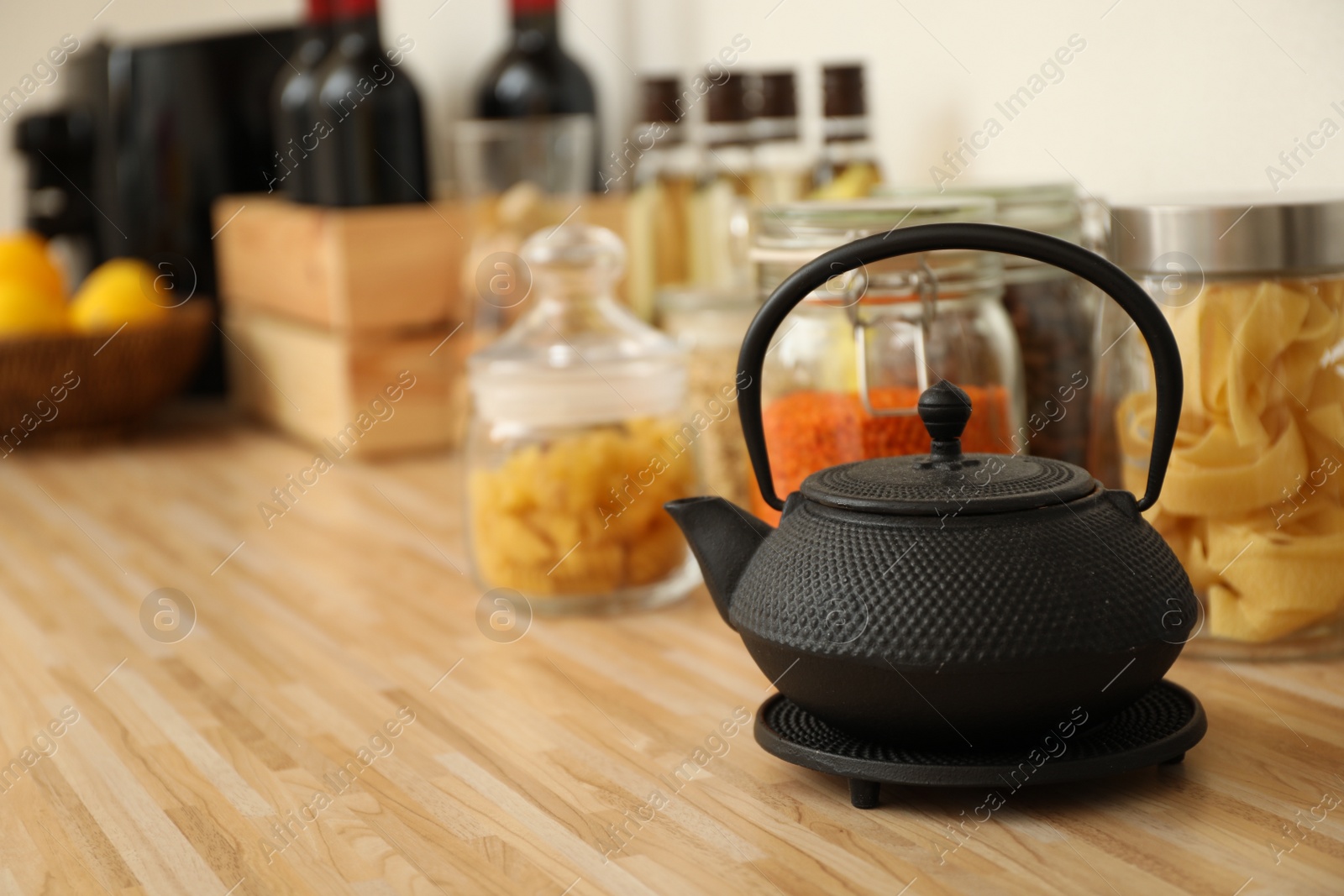 Photo of Black teapot on wooden countertop in kitchen, space for text. Interior element