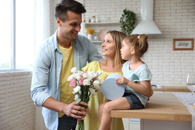 Happy man congratulating his little daughter and wife in kitchen