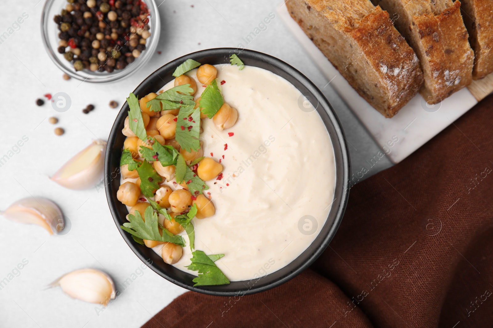 Photo of Flat lay composition of tasty chickpea soup in bowl, bread and spices served on light grey table