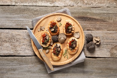 Photo of Delicious bruschettas with truffle sauce and sun dried tomatoes on wooden table, flat lay
