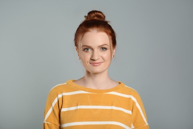 Photo of Candid portrait of happy red haired woman with charming smile on grey background