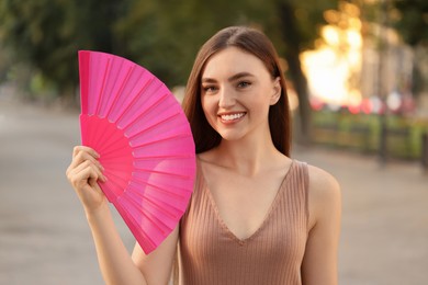 Photo of Happy woman holding hand fan in park
