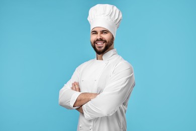 Photo of Happy young chef in uniform on light blue background