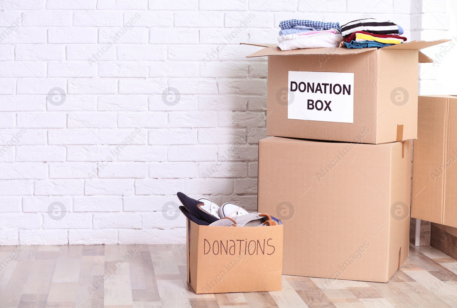 Photo of Donation boxes with shoes and clothes on floor indoors