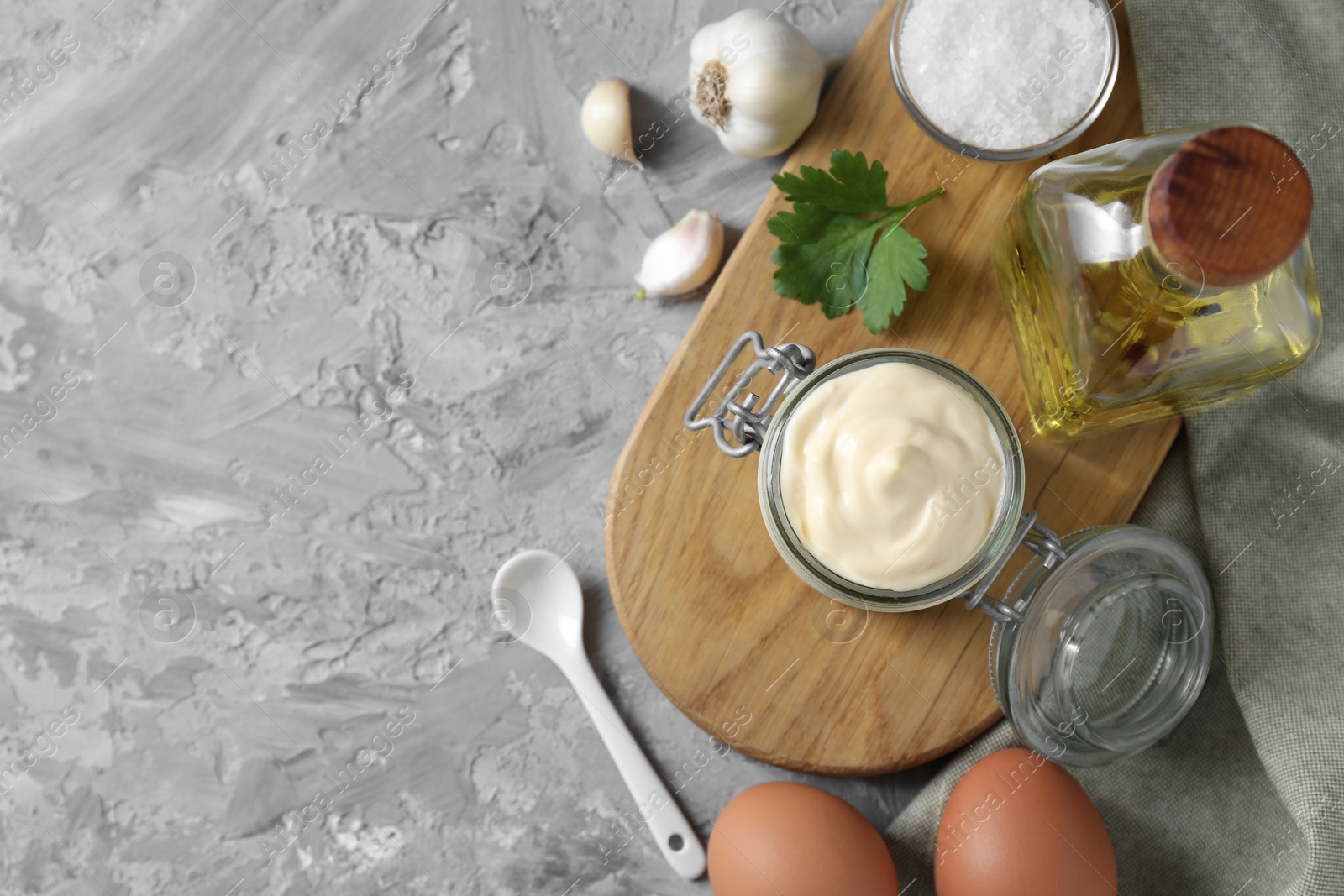 Photo of Tasty mayonnaise in jar and ingredients on gray textured table, flat lay. Space for text