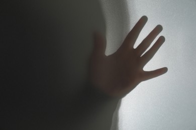 Silhouette of ghost behind glass against white background, closeup