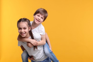 Photo of Happy brother and sister on orange background, space for text
