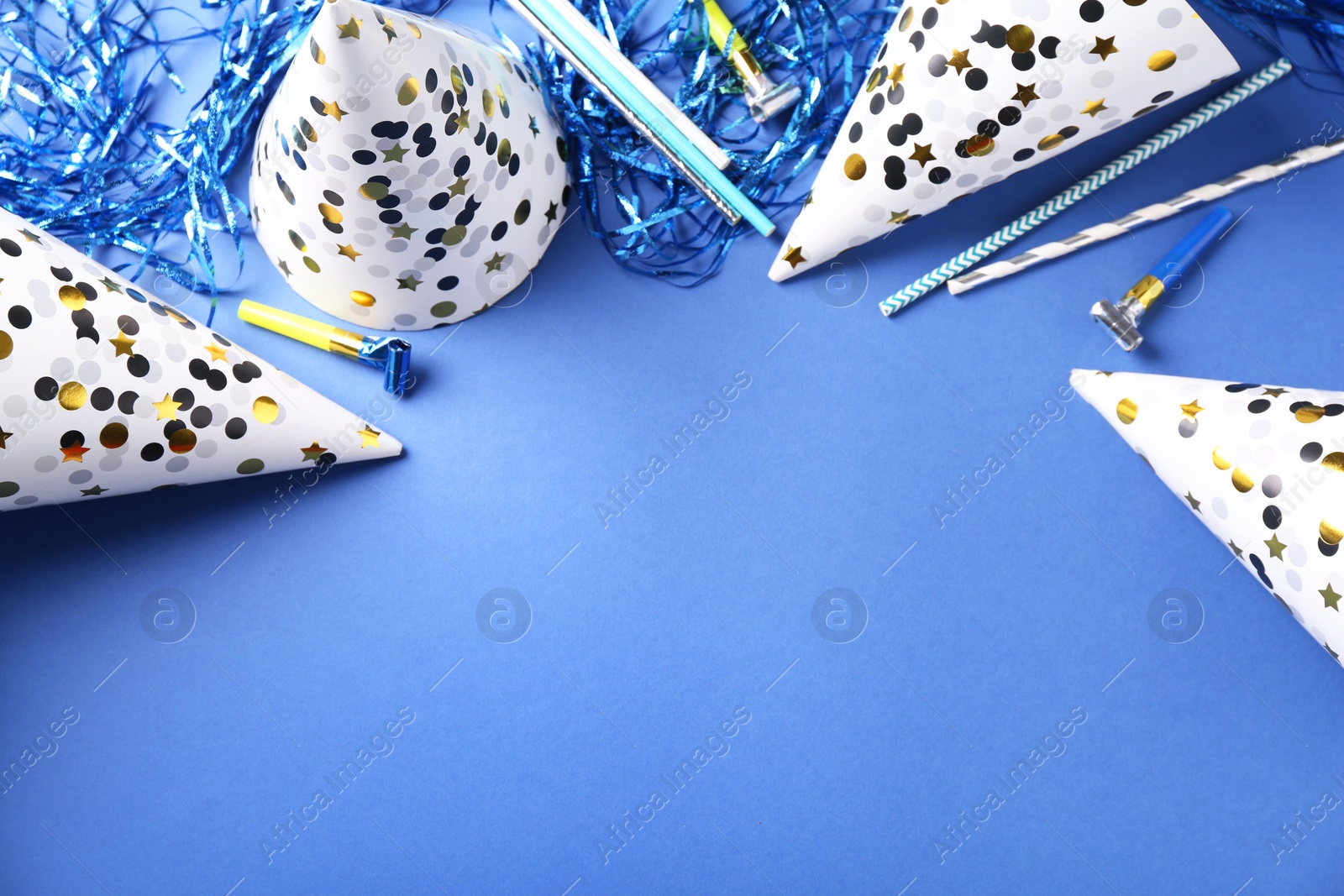 Photo of Party hats and other bright decor on blue background, flat lay. Space for text