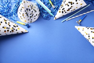 Photo of Party hats and other bright decor on blue background, flat lay. Space for text