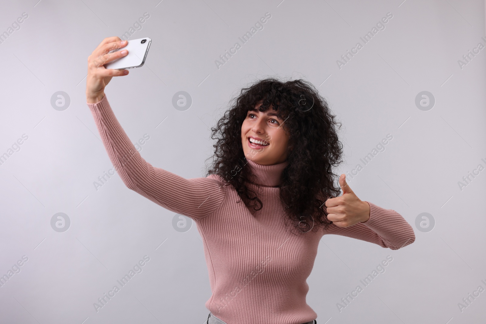 Photo of Beautiful young woman taking selfie on light grey background