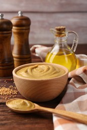 Photo of Bowl and spoon with tasty mustard sauce on wooden table