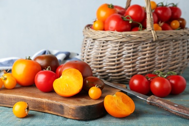 Composition with fresh ripe tomatoes and wicker basket on wooden table