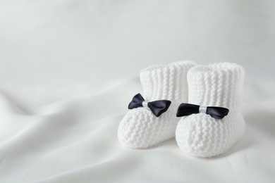 Handmade baby booties on light plaid. Space for text