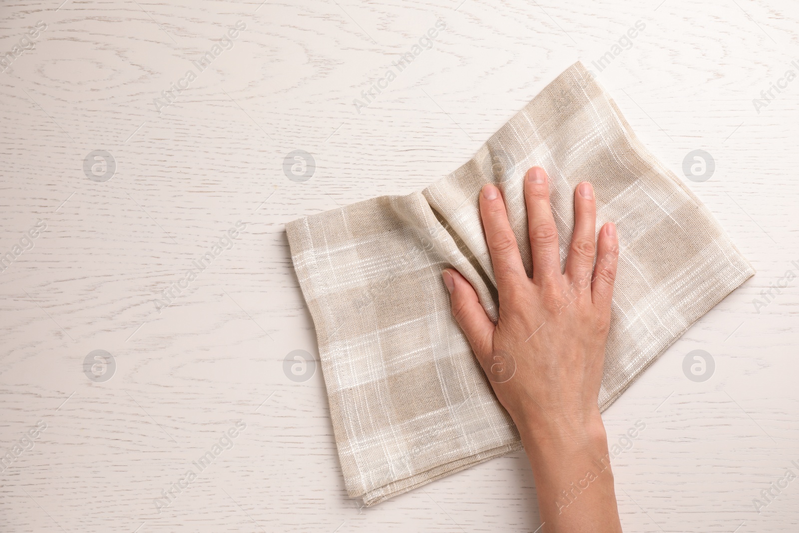 Photo of Woman wiping white wooden table with kitchen towel, top view. Space for text