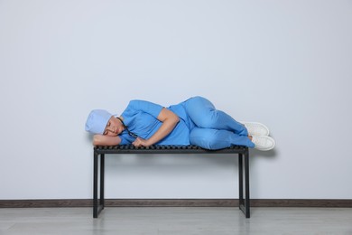 Photo of Tired young doctor sleeping on bench indoors