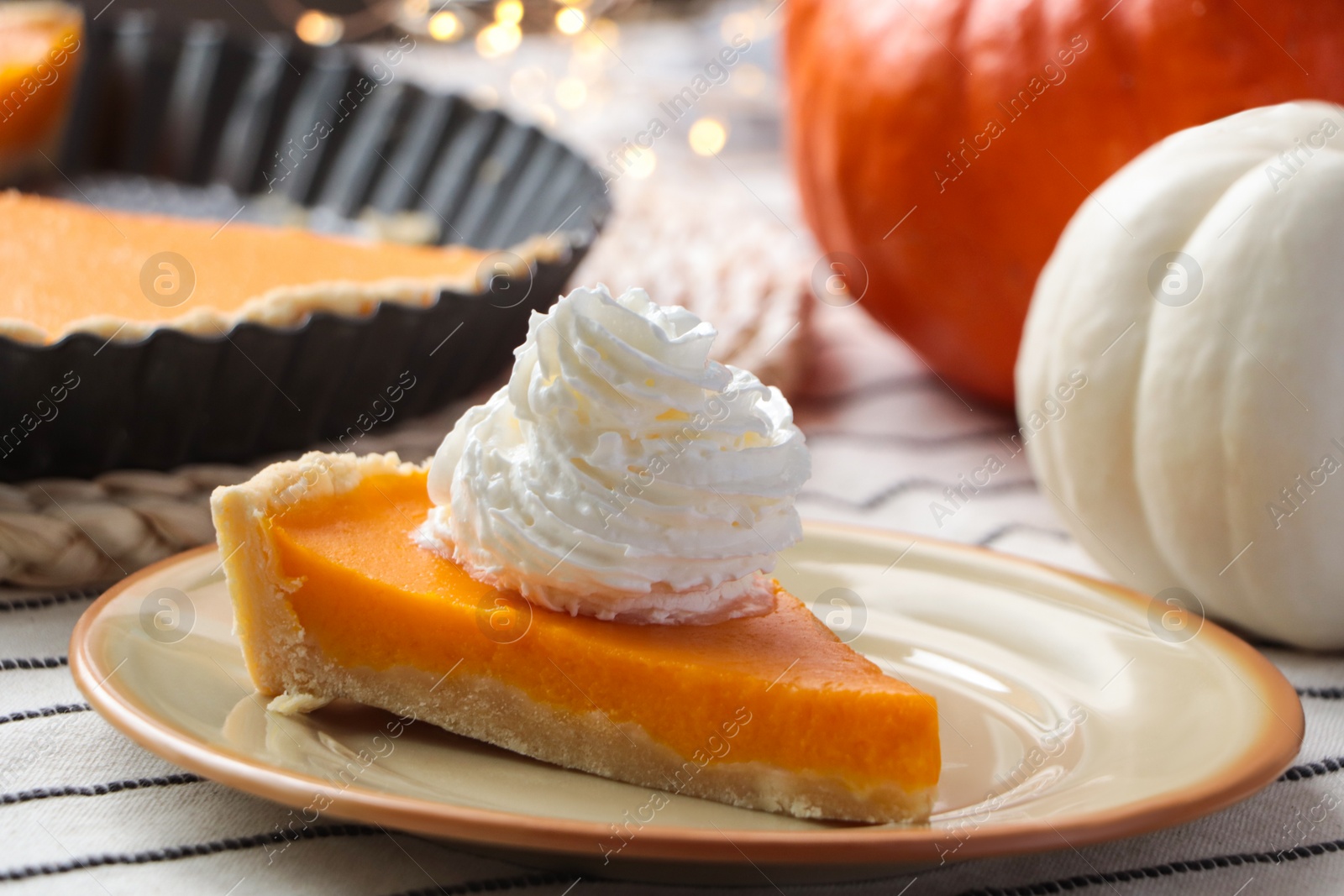 Photo of Piece of fresh homemade pumpkin pie with whipped cream on table