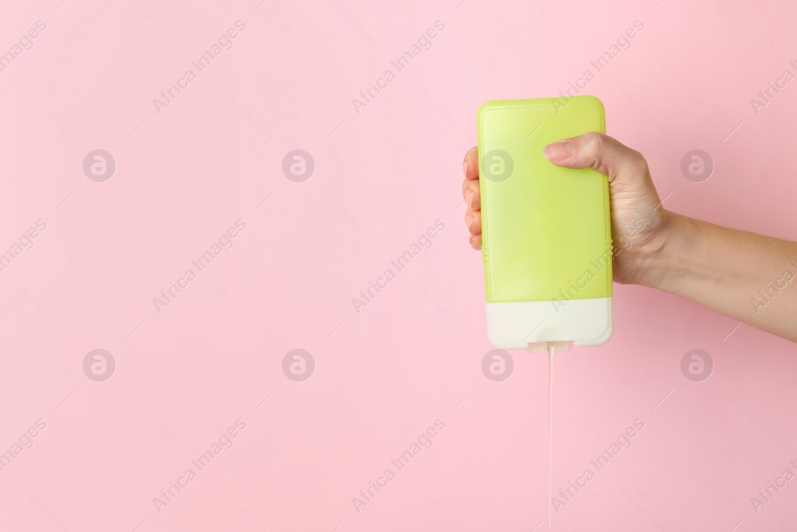 Photo of Woman pouring cosmetic product from bottle on color background, closeup. Space for text