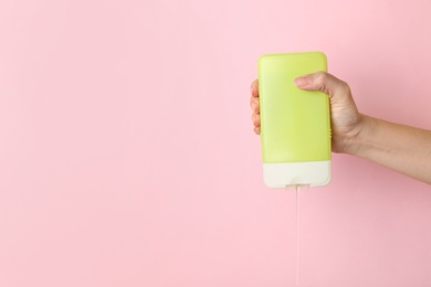 Woman pouring cosmetic product from bottle on color background, closeup. Space for text