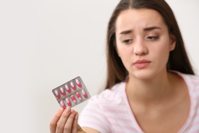 Photo of Young woman with pills on light background, space for text