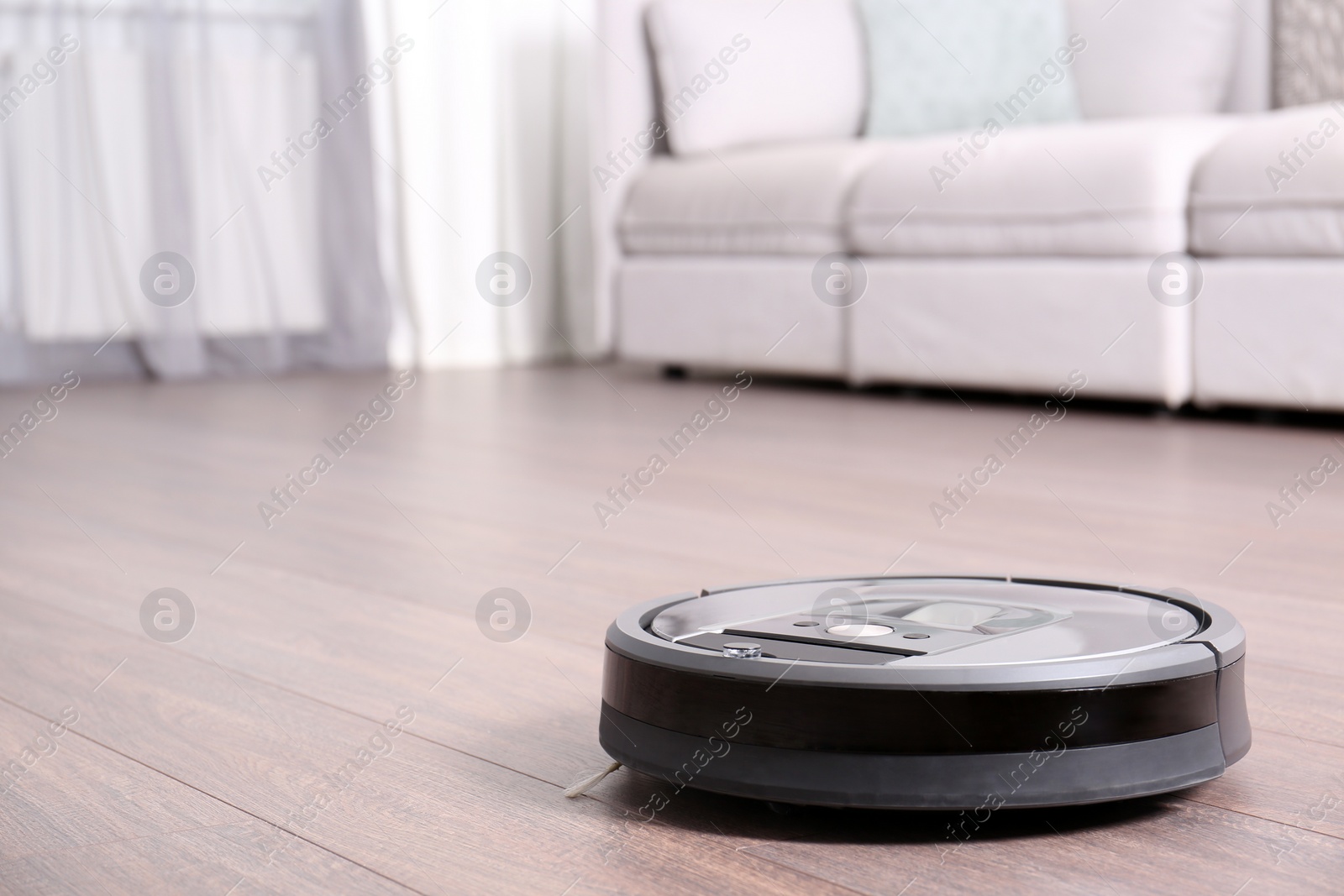 Photo of Hoovering floor with modern robotic vacuum cleaner indoors. Space for text