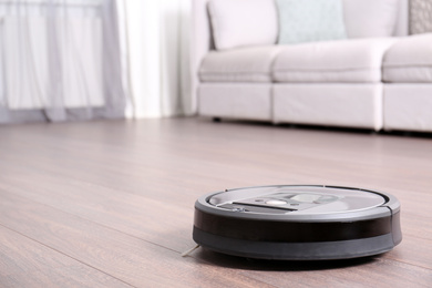 Hoovering floor with modern robotic vacuum cleaner indoors. Space for text