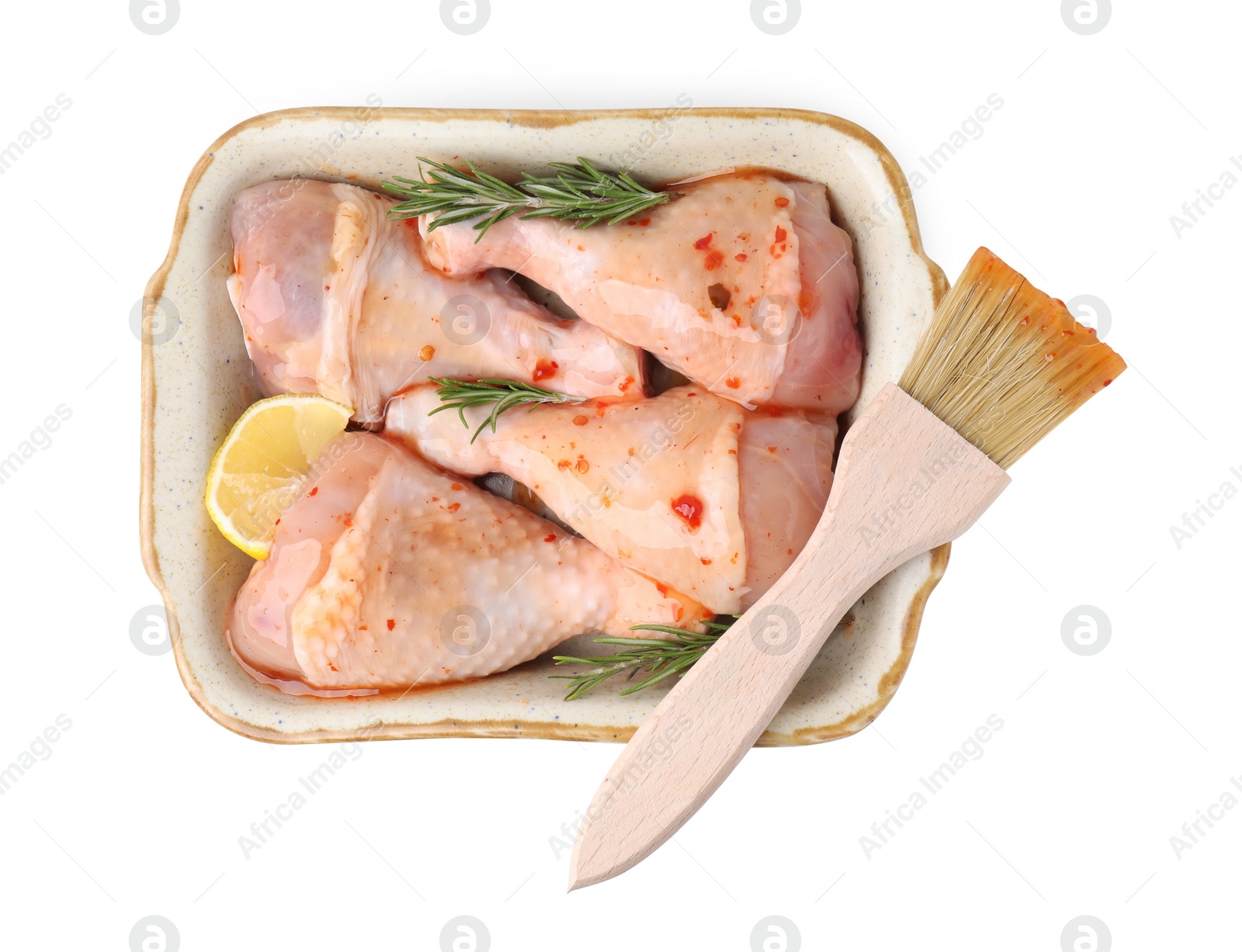 Photo of Raw marinated chicken drumsticks with rosemary, lemon and basting brush isolated on white, top view