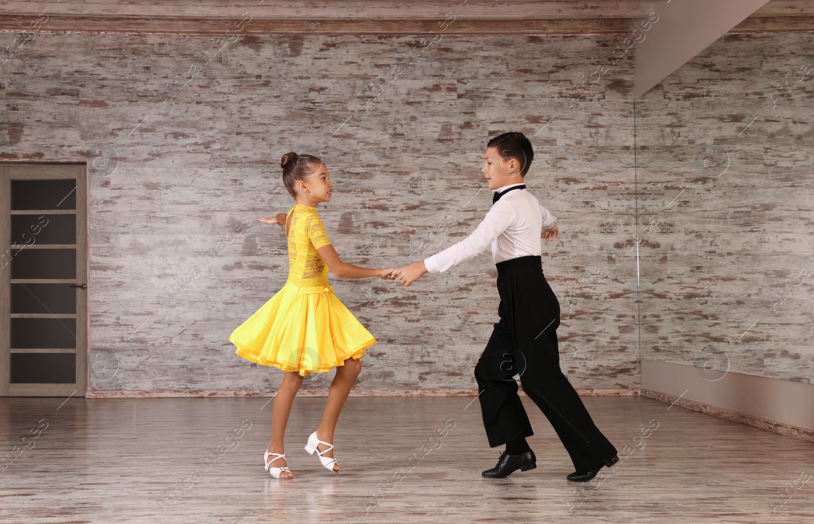 Photo of Beautifully dressed couple of kids dancing together in studio