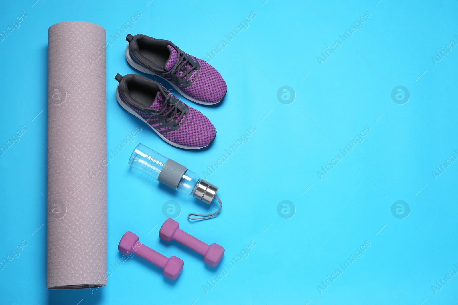 Photo of Exercise mat, dumbbells, bottle of water and shoes on turquoise background, flat lay. Space for text