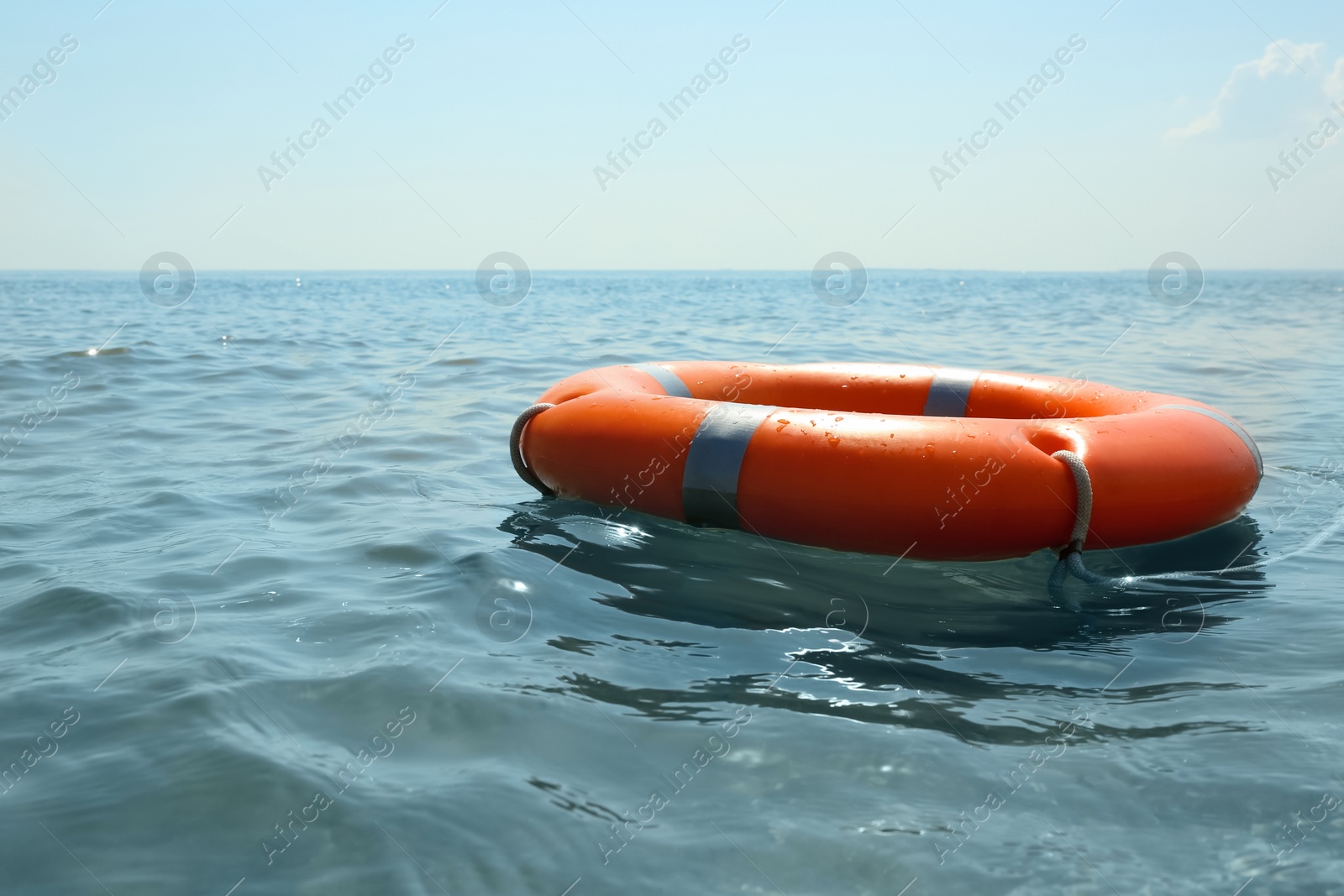 Photo of Orange life buoy floating in sea. Emergency rescue equipment