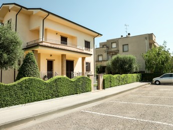 Residential building with beautiful green hedge on sunny day