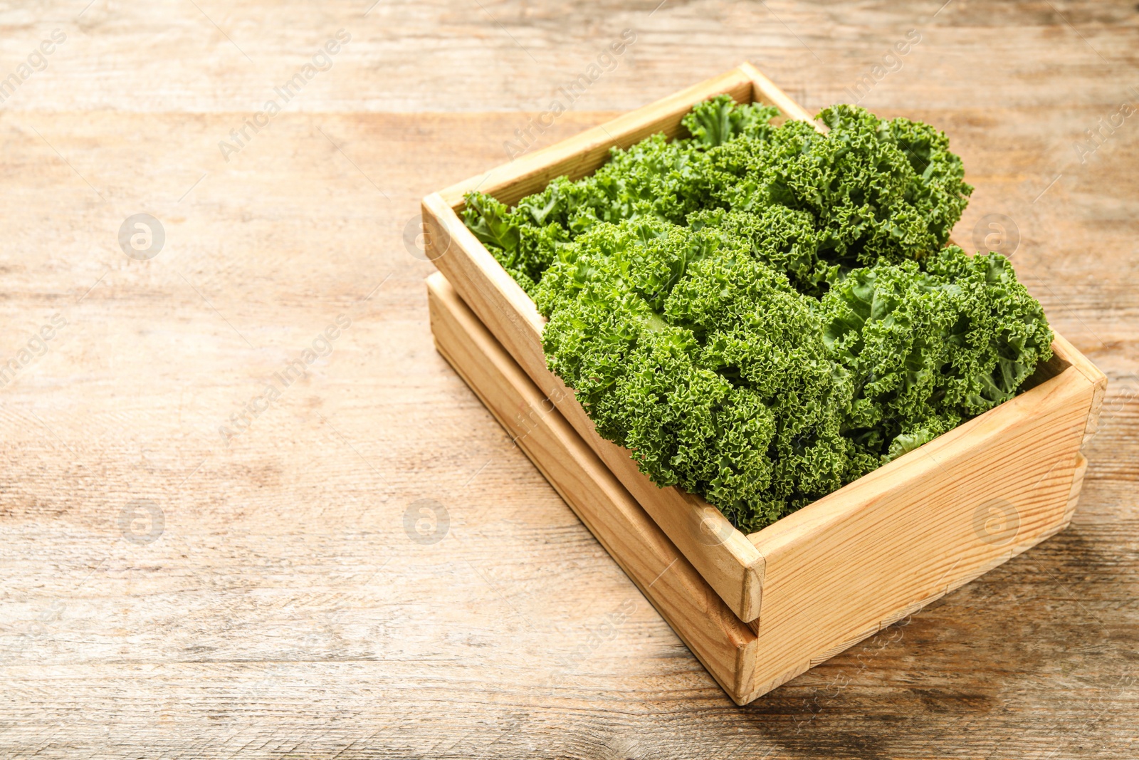 Photo of Fresh kale leaves on wooden table. Space for text