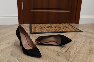 Photo of Stylish female shoes near door mat in hall