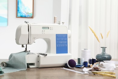 Photo of White sewing machine, cloth and craft accessories on wooden table indoors